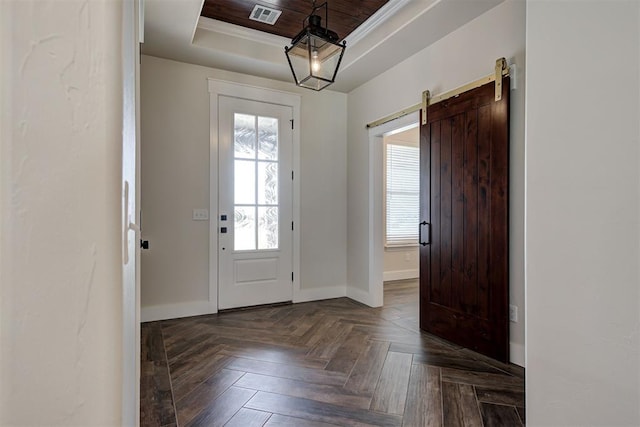 foyer featuring a tray ceiling, visible vents, a barn door, and baseboards