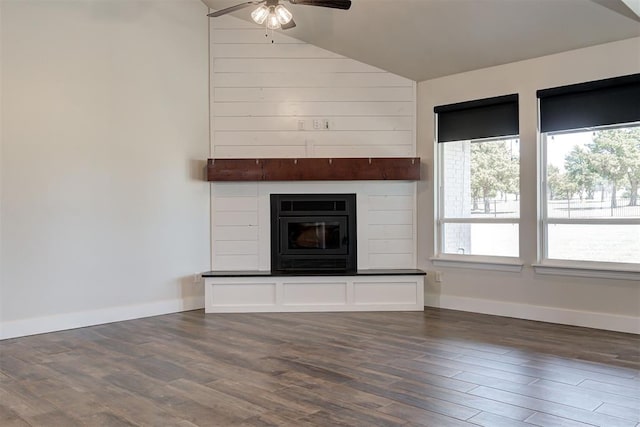 unfurnished living room with a glass covered fireplace, dark wood-type flooring, baseboards, and vaulted ceiling