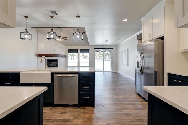 kitchen with a sink, stainless steel appliances, dark cabinets, and light countertops