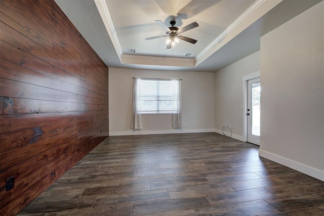 spare room with a raised ceiling, wood finished floors, visible vents, and a wealth of natural light