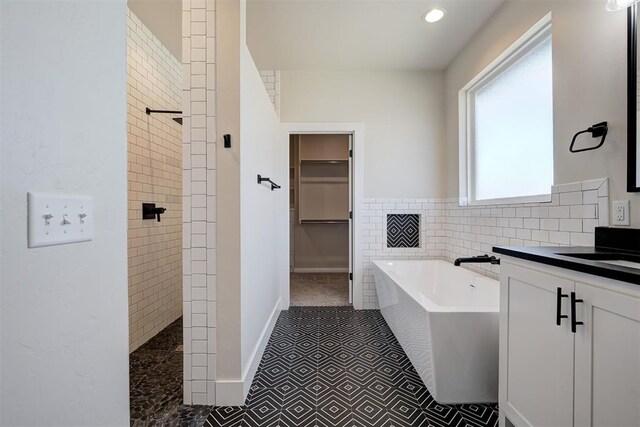 bathroom featuring a spacious closet, a washtub, vanity, and walk in shower