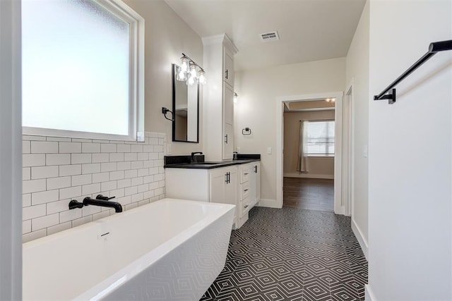 full bathroom with visible vents, vanity, and a washtub