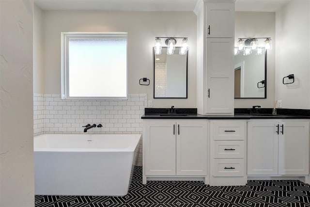 full bathroom with double vanity, a freestanding bath, tile walls, and a sink