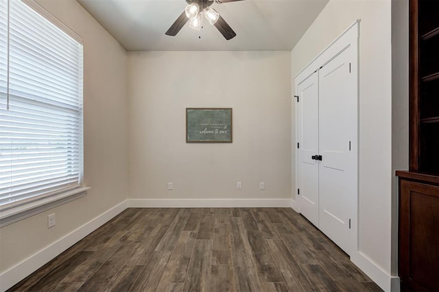 unfurnished bedroom with a closet, baseboards, and dark wood finished floors