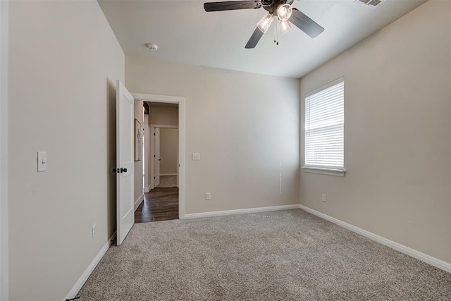 carpeted spare room featuring visible vents, a ceiling fan, and baseboards