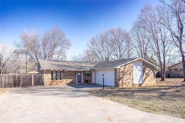 view of front of home featuring a garage, fence, brick siding, and driveway