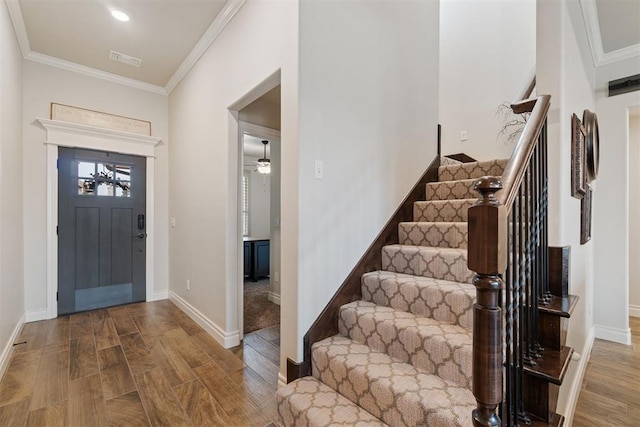 foyer entrance featuring stairs, wood finished floors, visible vents, and ornamental molding