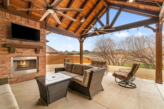 view of patio / terrace featuring a gazebo, an outdoor living space with a fireplace, ceiling fan, and fence