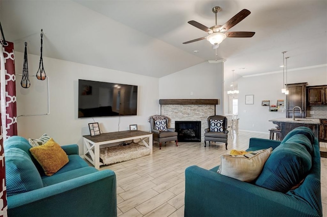 living room with a ceiling fan, baseboards, light wood-style flooring, a stone fireplace, and vaulted ceiling