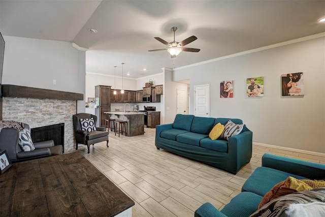 living area with a ceiling fan, baseboards, wood finish floors, a fireplace, and ornamental molding