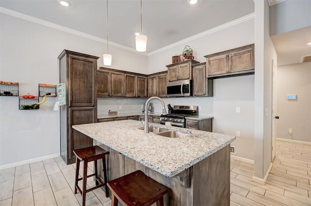 kitchen featuring decorative light fixtures, a sink, stainless steel appliances, and ornamental molding