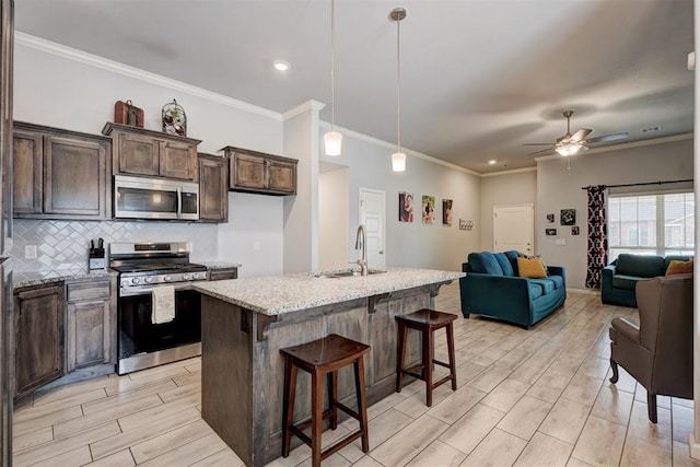 kitchen featuring decorative backsplash, open floor plan, appliances with stainless steel finishes, and a sink