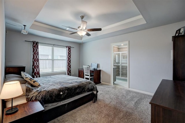 carpeted bedroom with baseboards, a tray ceiling, ceiling fan, crown molding, and connected bathroom