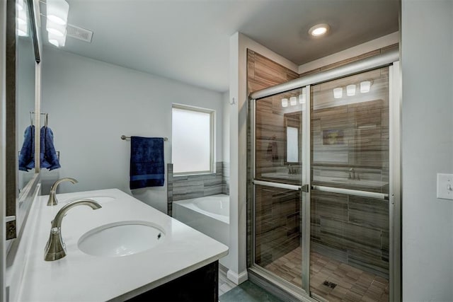 bathroom featuring double vanity, a bathing tub, a stall shower, and a sink