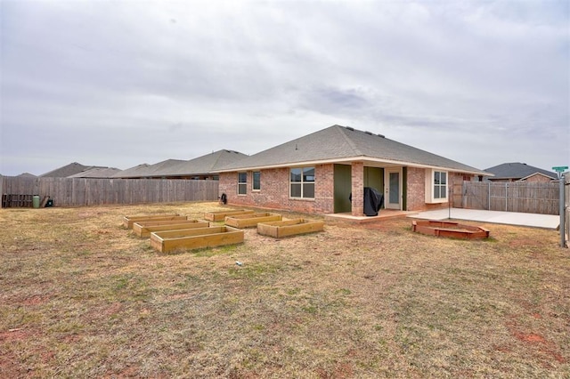 back of property featuring a lawn, a patio, a fenced backyard, a garden, and brick siding