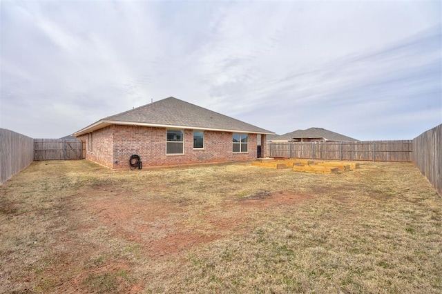 rear view of property with a fenced backyard, brick siding, and a lawn