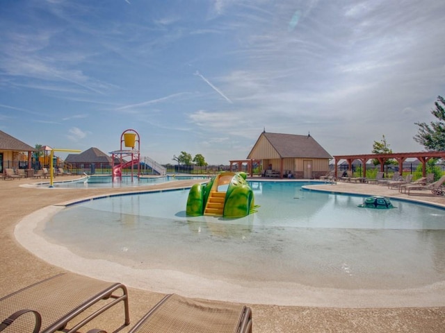 community pool with a pergola, fence, a water slide, a water play area, and a patio area