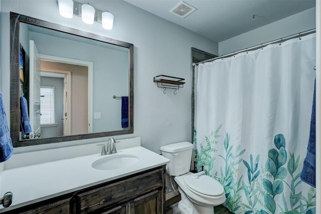 bathroom with vanity, toilet, and visible vents