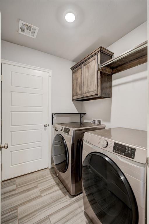 washroom featuring washer and dryer, light wood-style floors, cabinet space, and visible vents