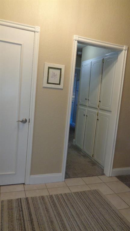 hallway with baseboards and light tile patterned flooring