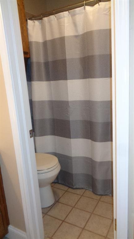 bathroom featuring a shower with shower curtain, toilet, and tile patterned flooring