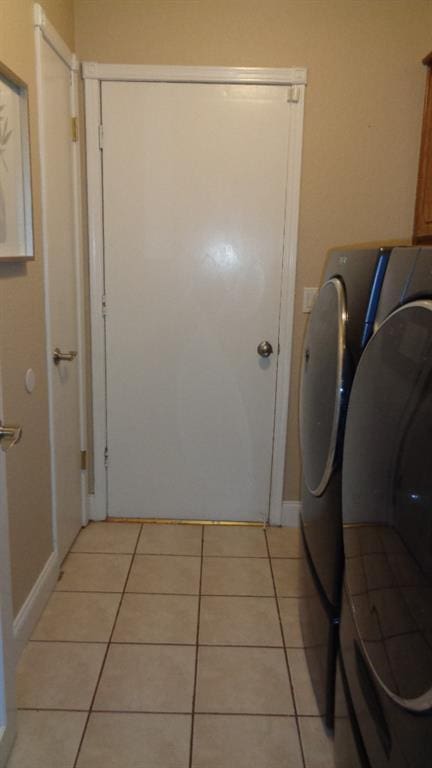 washroom with laundry area, light tile patterned floors, separate washer and dryer, and baseboards