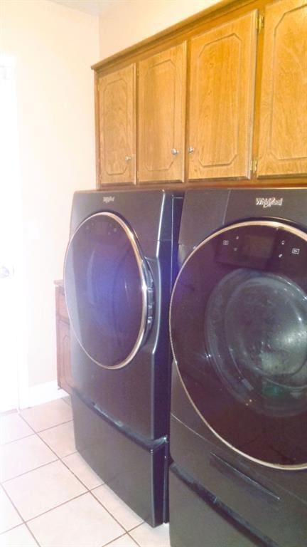 laundry area featuring light tile patterned flooring, cabinet space, baseboards, and separate washer and dryer