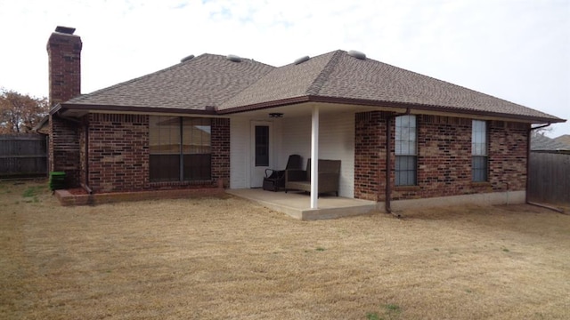 rear view of property with brick siding, a yard, a patio, and fence