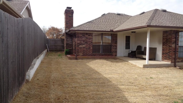 back of house with a yard, a patio area, brick siding, and a fenced backyard