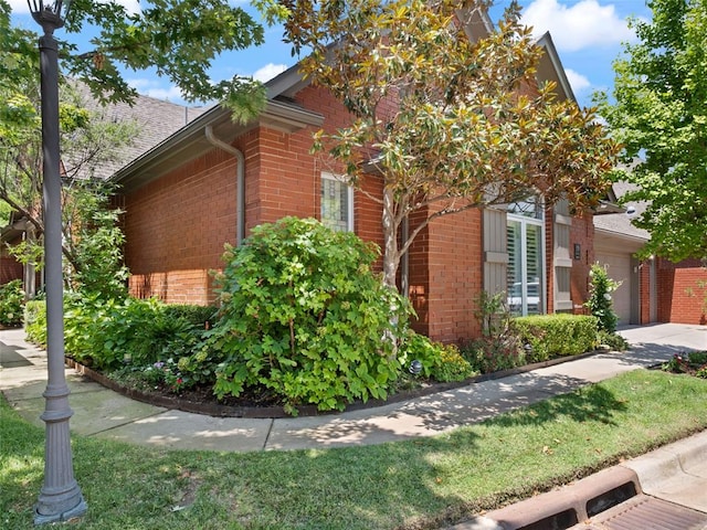 view of property exterior with a garage, brick siding, and a shingled roof