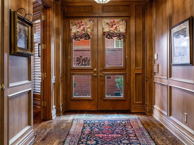 foyer with french doors, wooden walls, and dark wood finished floors