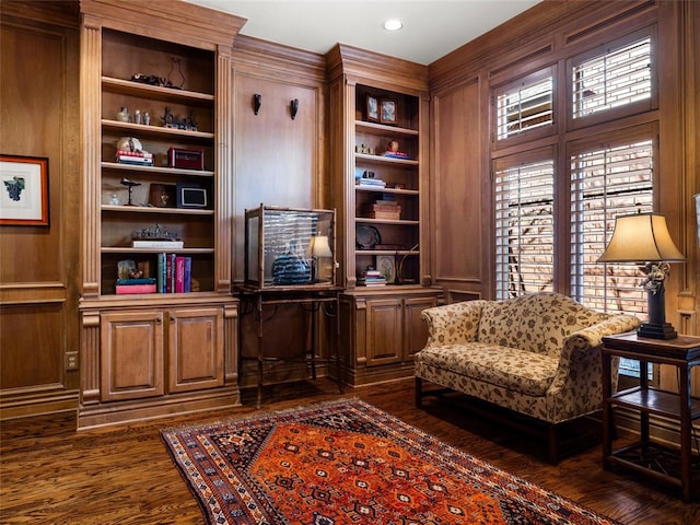 sitting room with dark wood finished floors and built in shelves