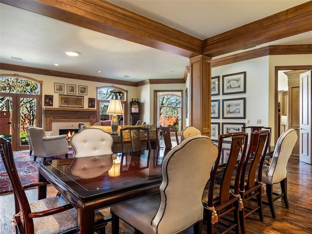 dining space with dark wood finished floors, a warm lit fireplace, french doors, and ornamental molding