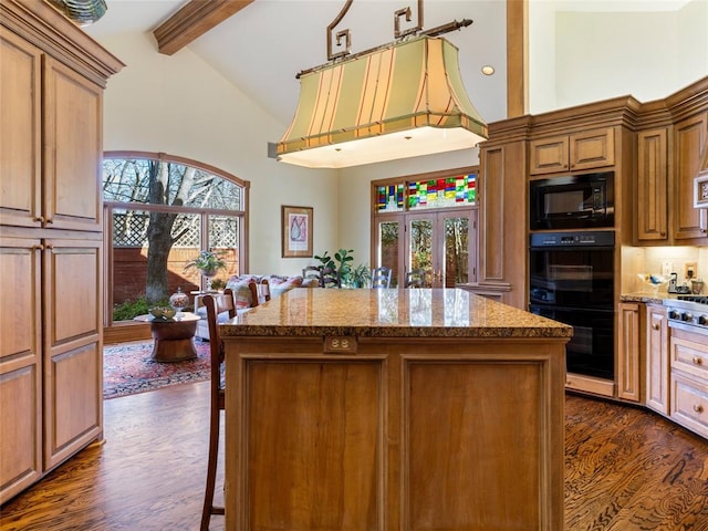 kitchen featuring beamed ceiling, dark wood-type flooring, black appliances, a center island, and stone counters