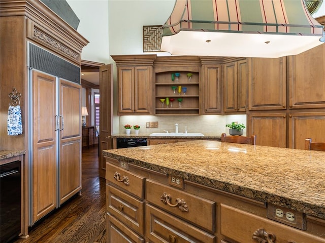 kitchen with paneled built in refrigerator, dark wood finished floors, open shelves, a high ceiling, and a sink