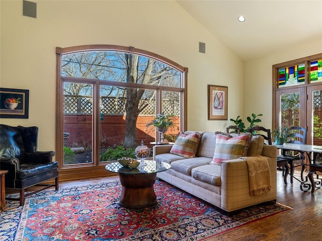 living area with visible vents, recessed lighting, high vaulted ceiling, and wood finished floors