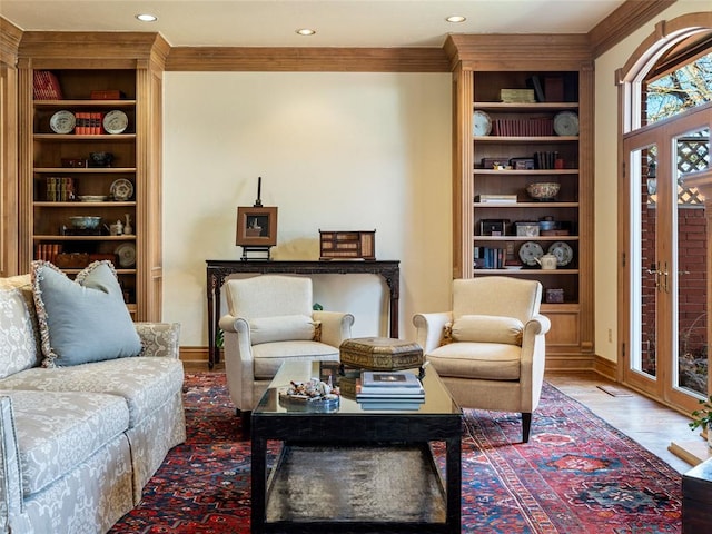 living area with built in features, crown molding, baseboards, and wood finished floors