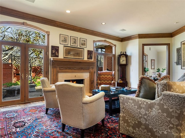 sitting room featuring french doors, plenty of natural light, a warm lit fireplace, and wood finished floors