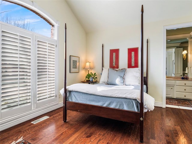 bedroom with lofted ceiling, wood finished floors, visible vents, and connected bathroom