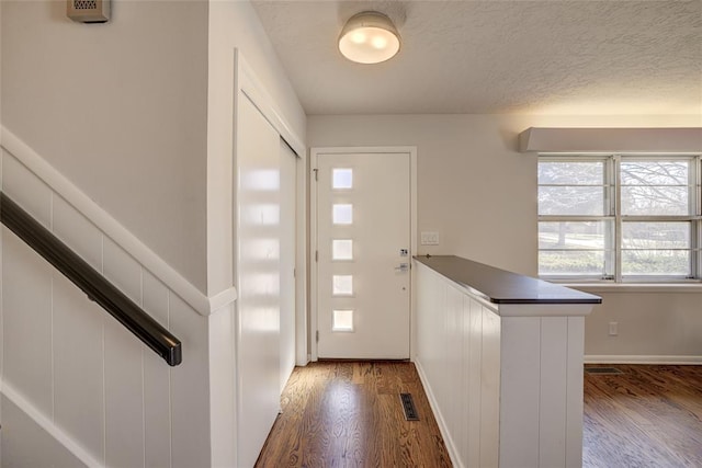 entrance foyer with visible vents, a textured ceiling, dark wood finished floors, and stairs