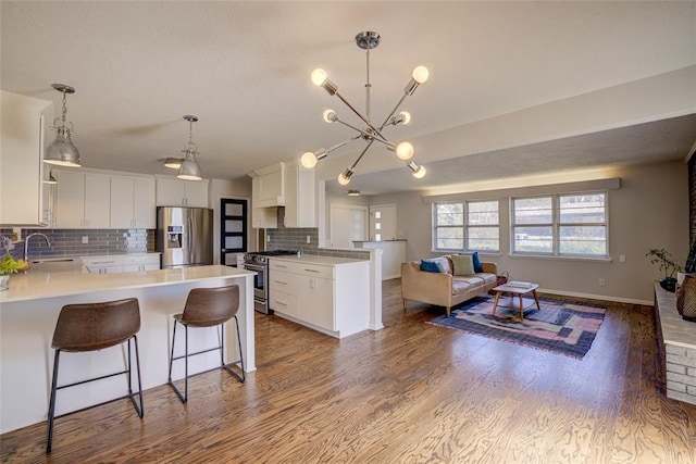 kitchen with a sink, open floor plan, wood finished floors, appliances with stainless steel finishes, and a peninsula