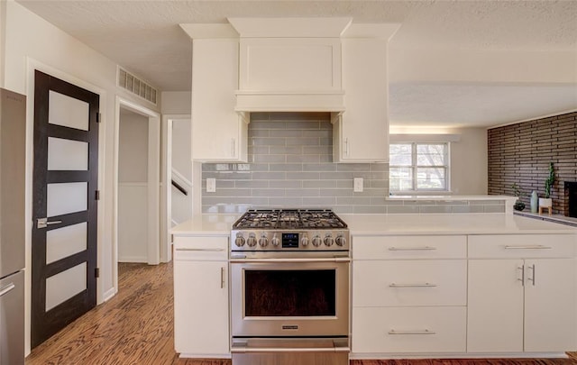 kitchen with visible vents, white cabinetry, stainless steel gas range, and light countertops