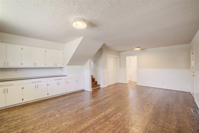 bonus room with visible vents, stairs, wainscoting, wood finished floors, and a textured ceiling