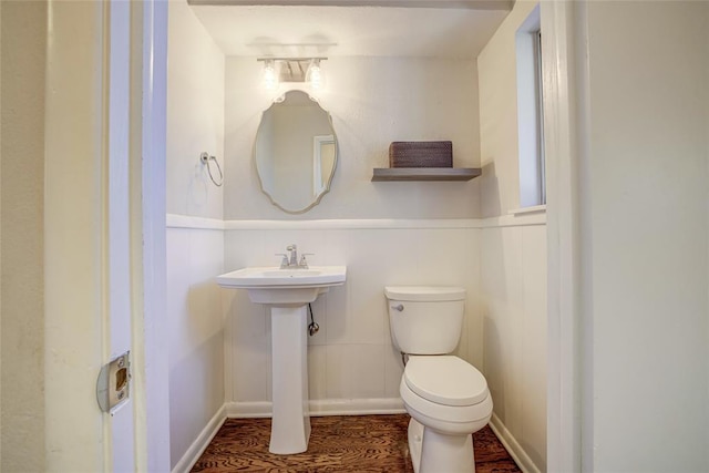 half bath featuring toilet and a wainscoted wall