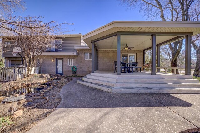 exterior space featuring fence, brick siding, and ceiling fan