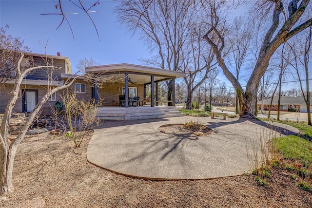 back of house featuring a patio, brick siding, driveway, and ceiling fan