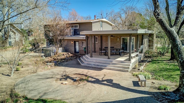 rear view of house featuring brick siding and fence