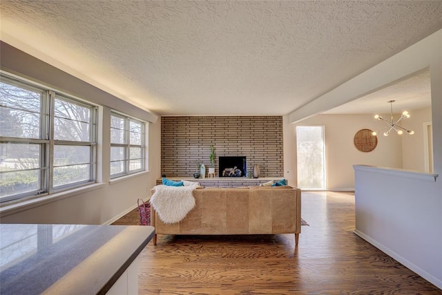 living area featuring baseboards, dark wood-style floors, a textured ceiling, and a notable chandelier