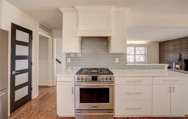 kitchen with light wood finished floors, light countertops, white cabinetry, gas range, and visible vents