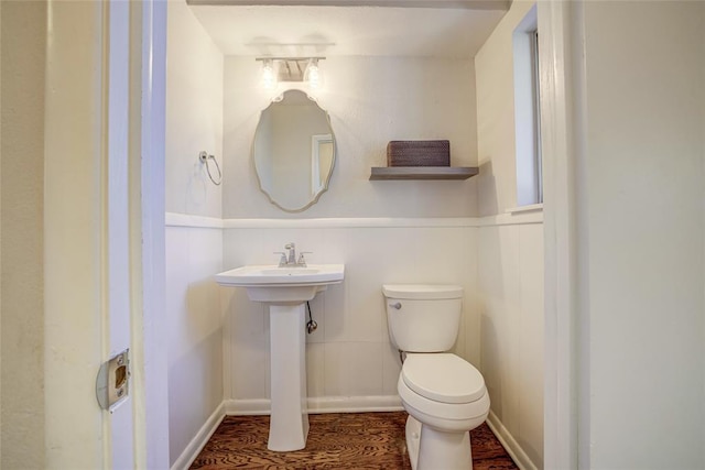 bathroom featuring a wainscoted wall, toilet, and wood finished floors